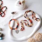 A beautiful flat lay display of handmade gemstone bracelets and necklaces on a decorative tray.